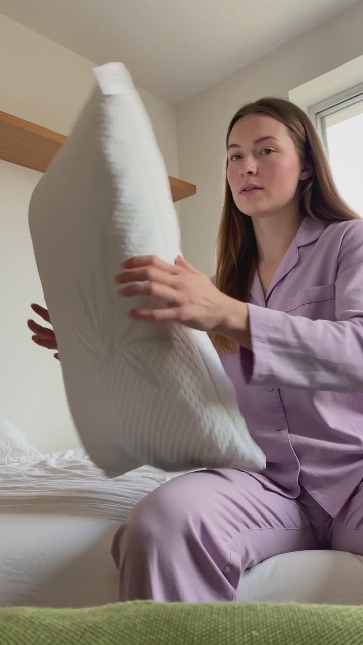 Femeie în pijama care își aranjează perna anatomică RestLab pe pat